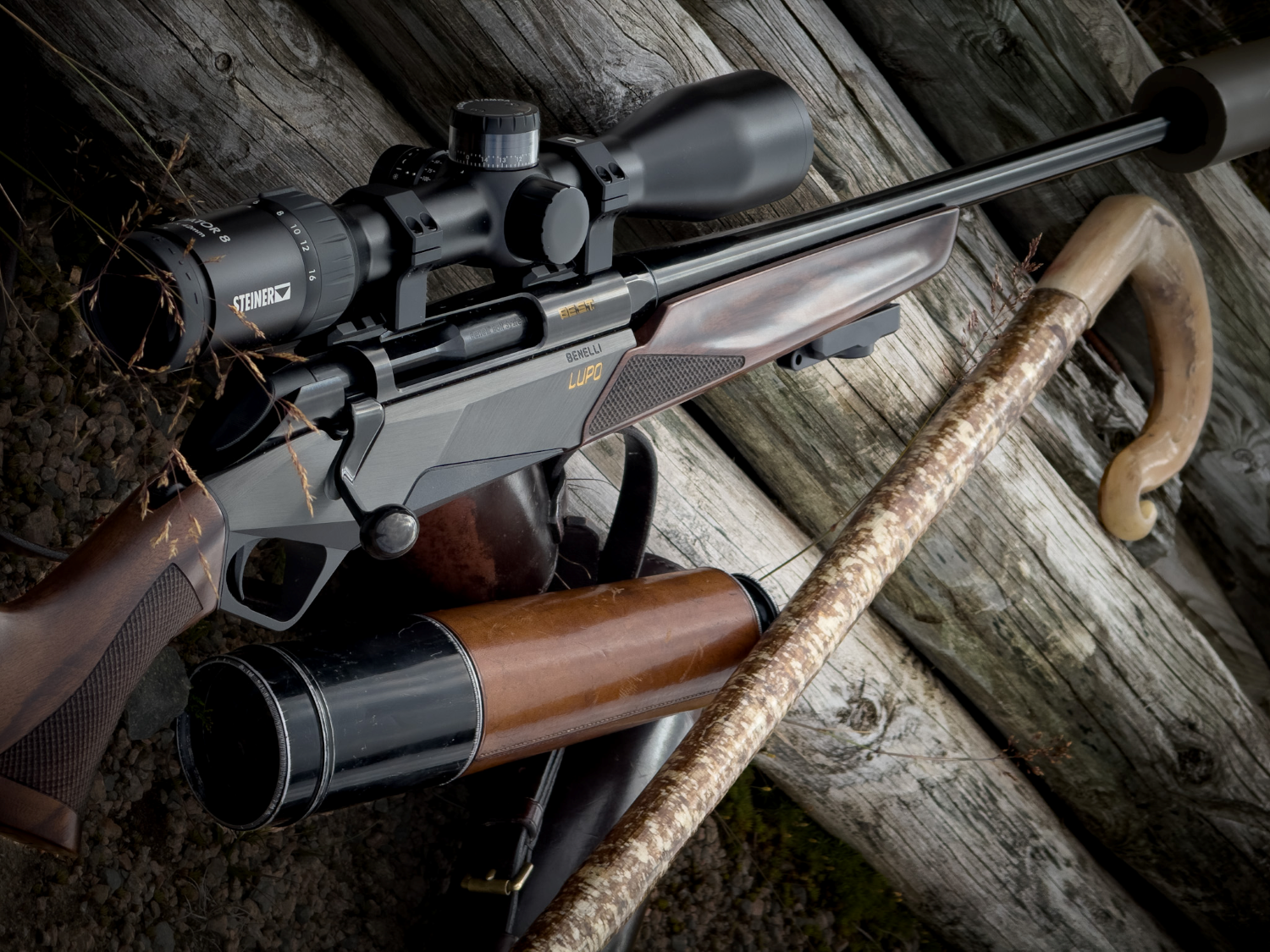 Lupo bolt-action rifle on logs with a scotish walking stick and steiner scope