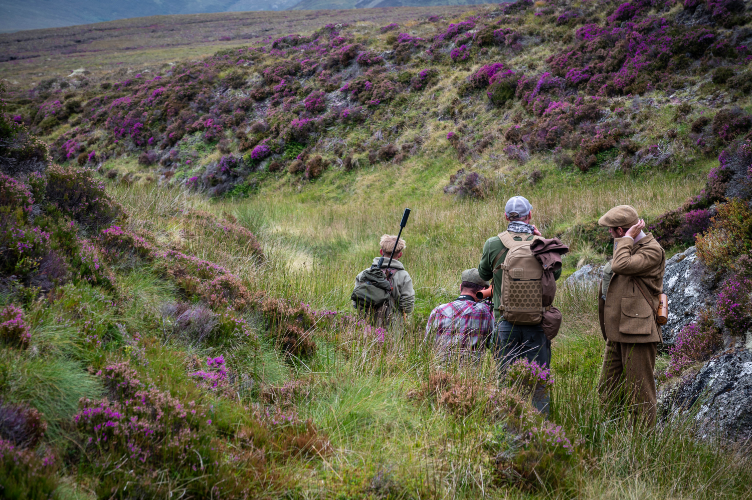Hunters in scotish heather walking through the landscape 