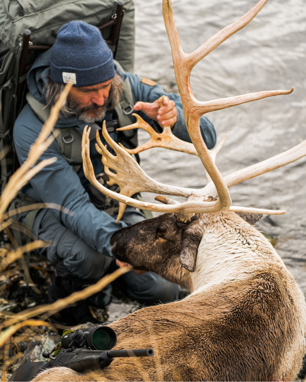 Donnie Vincent takes a moment to appreciate his magnificent caribou kill while on Adak Island, Alaska next to the Bering Sea.
